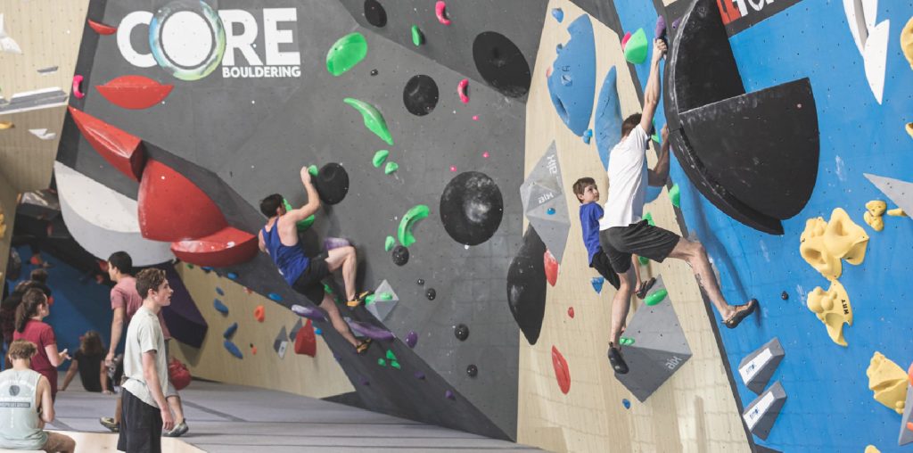 People bouldering on colorful climbing walls at the Core Bouldering indoor facility